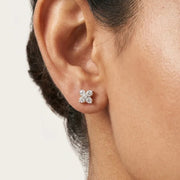 Close-up of a woman wearing a diamond earring on a neutral background
